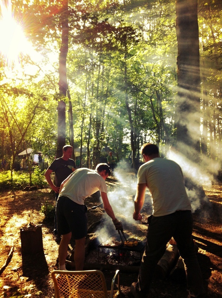 Three men grilling food in the camping site.