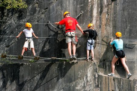 Adult and children walking on a rope bridge during their Via Ferrata adventure holiday in France