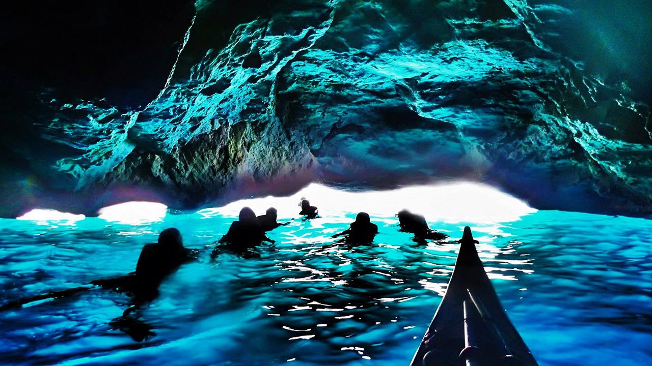 People swimming under a cave