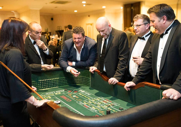 Men in suit and a woman playing casino during their corporate event.