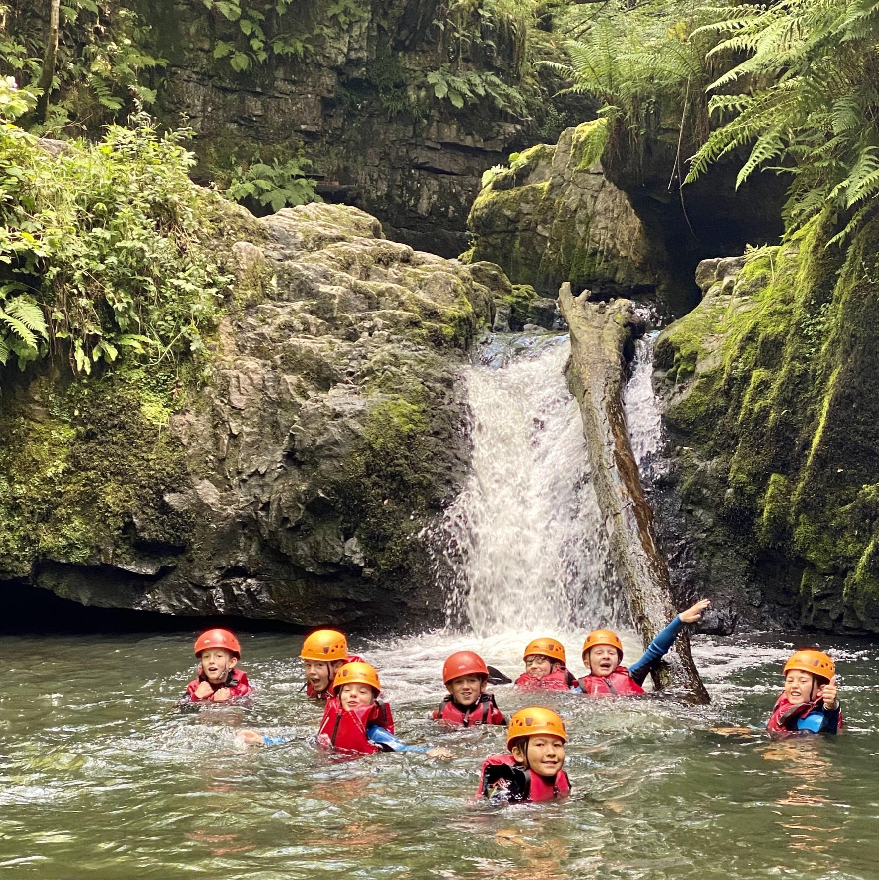 Young people swimming in the waterfall during their school residential trip.