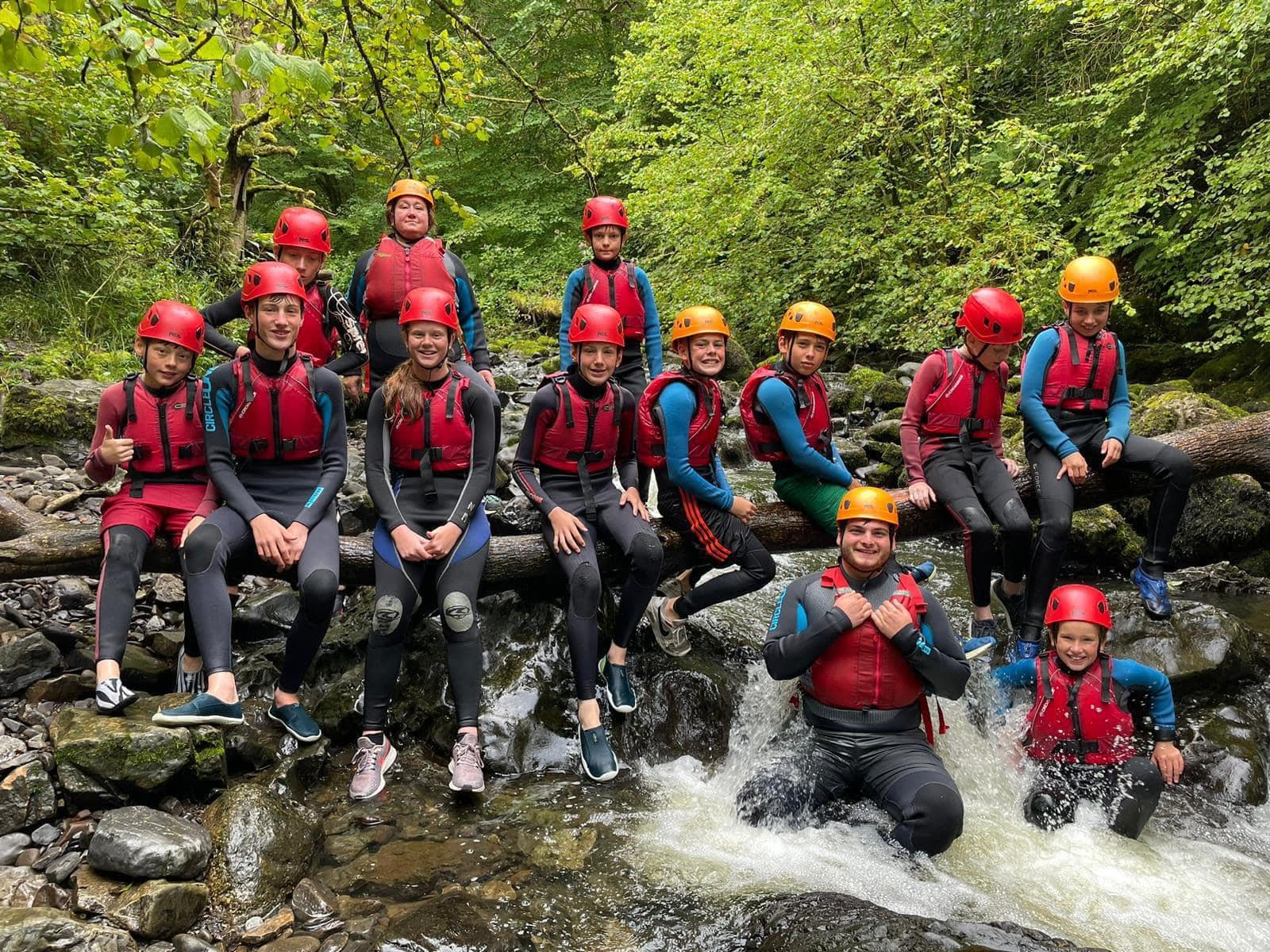 Group of young people posing for a photo in the river during their school residential trip.