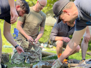 Group of men making fire in their wild camping stag do adventure in Cardiff