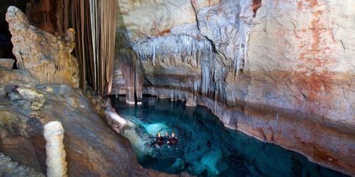 People enjoying the pristine water inside a cave in Majorca