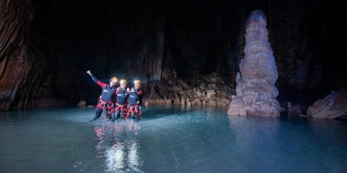 Three people taking a picture in the middle of the cave's water
