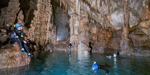 People swimming in the water inside the cave