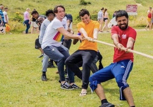 Team of boys pulling the rope during their tug of war youth group activity.