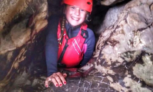 A young girl inside a cave for their school activity.