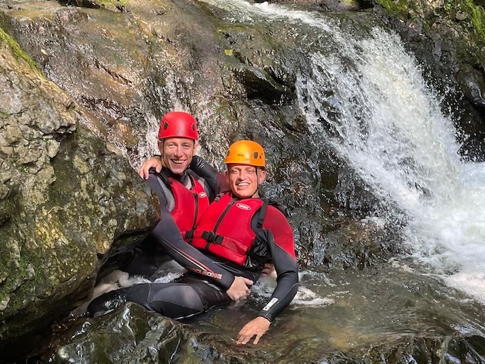 Two persons having fun gorge walking in Wales.